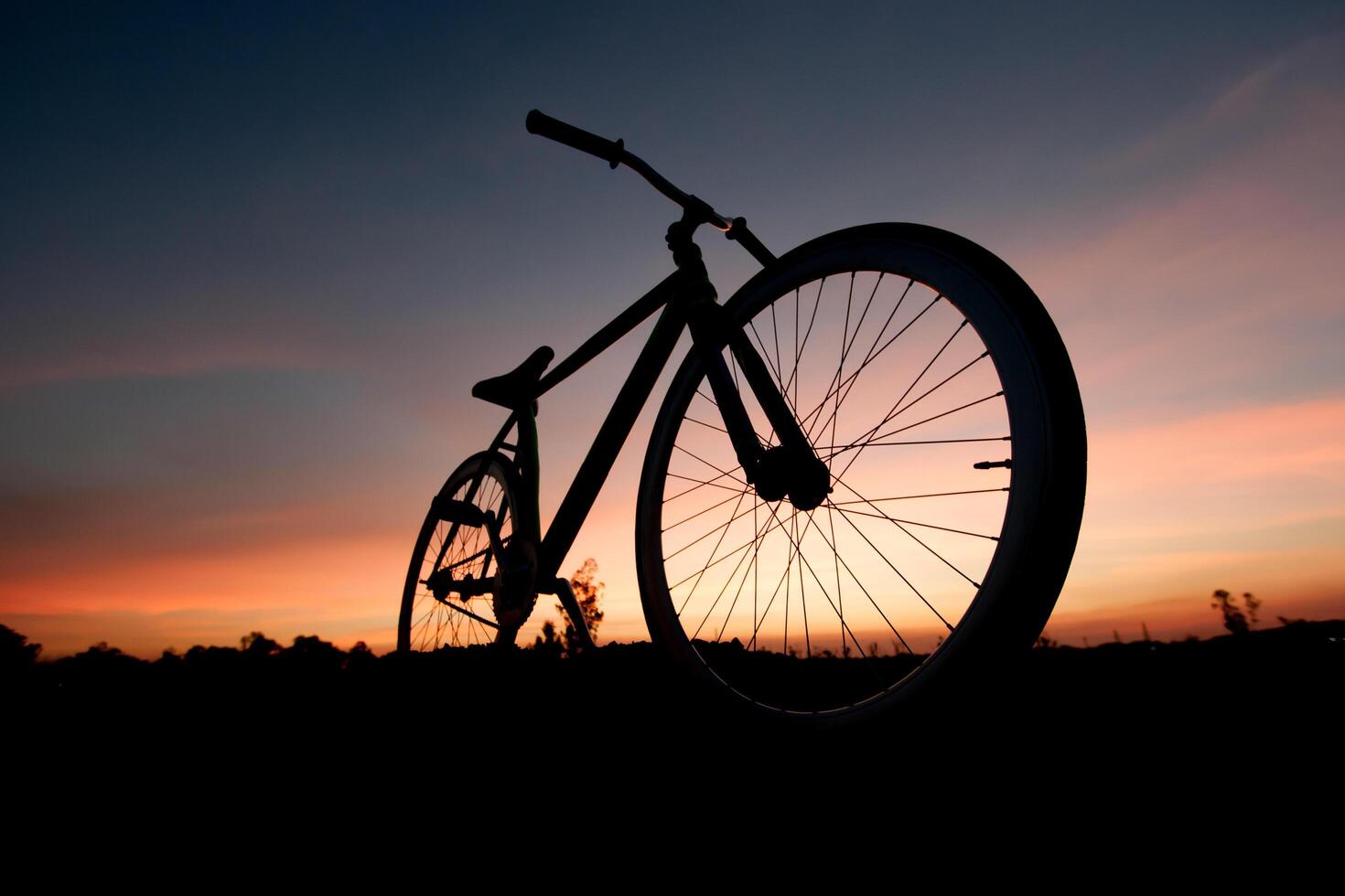 A bicycle is silhouetted against a sunset sky photo