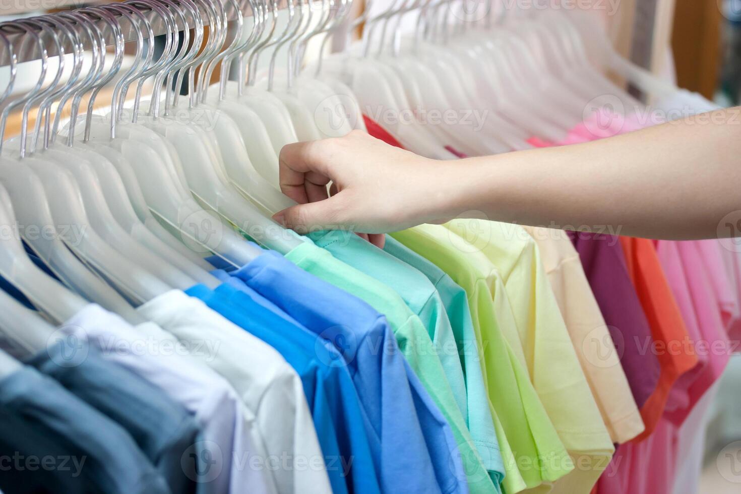 A person is picking out a shirt from a rack photo