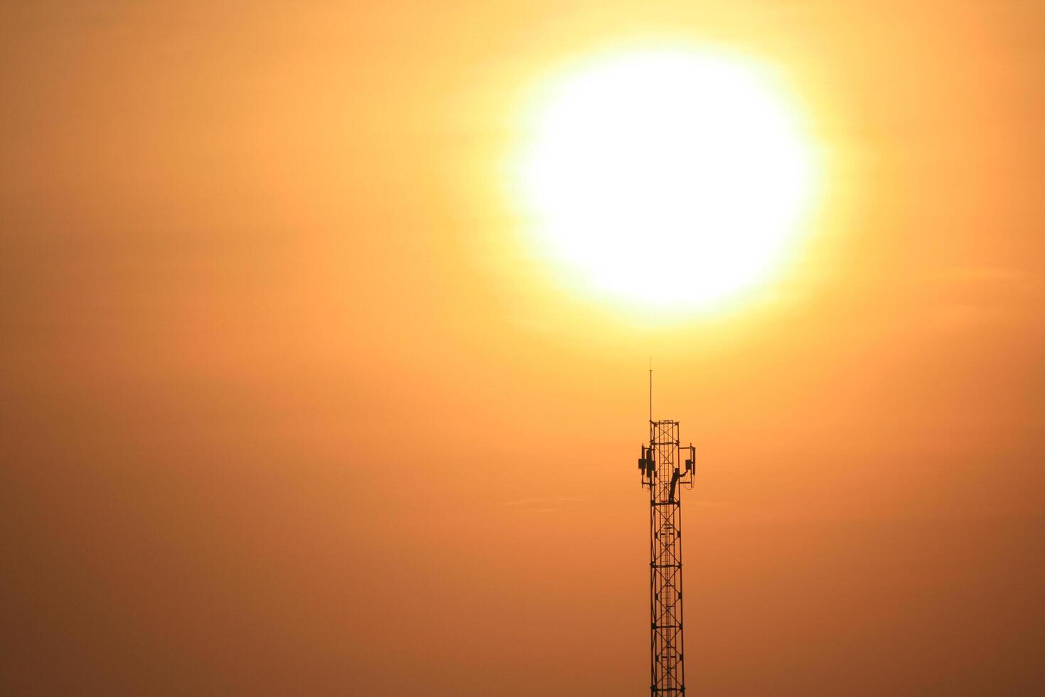A cell tower with the sun behind it photo