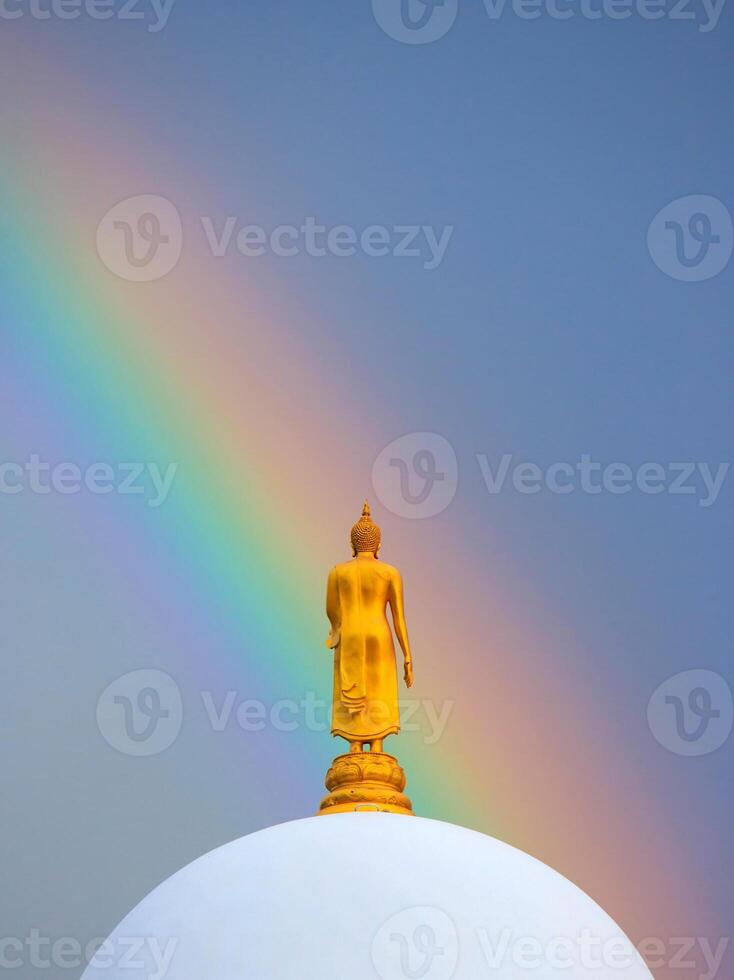 A buddha statue on top of a dome with a rainbow in the sky photo