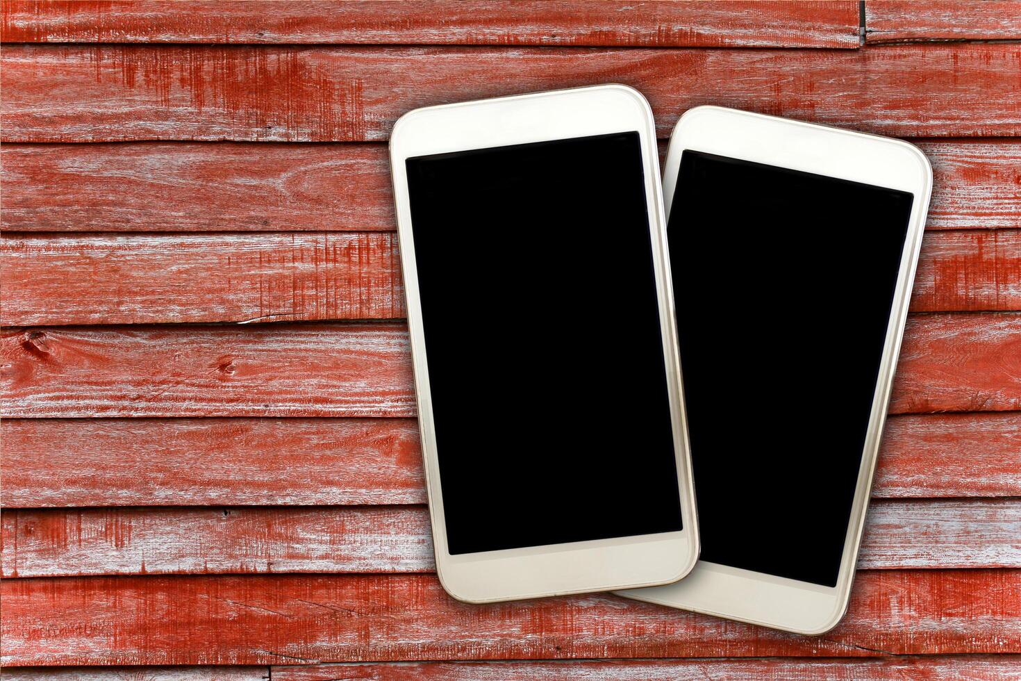 Two smartphones on a red wooden background photo