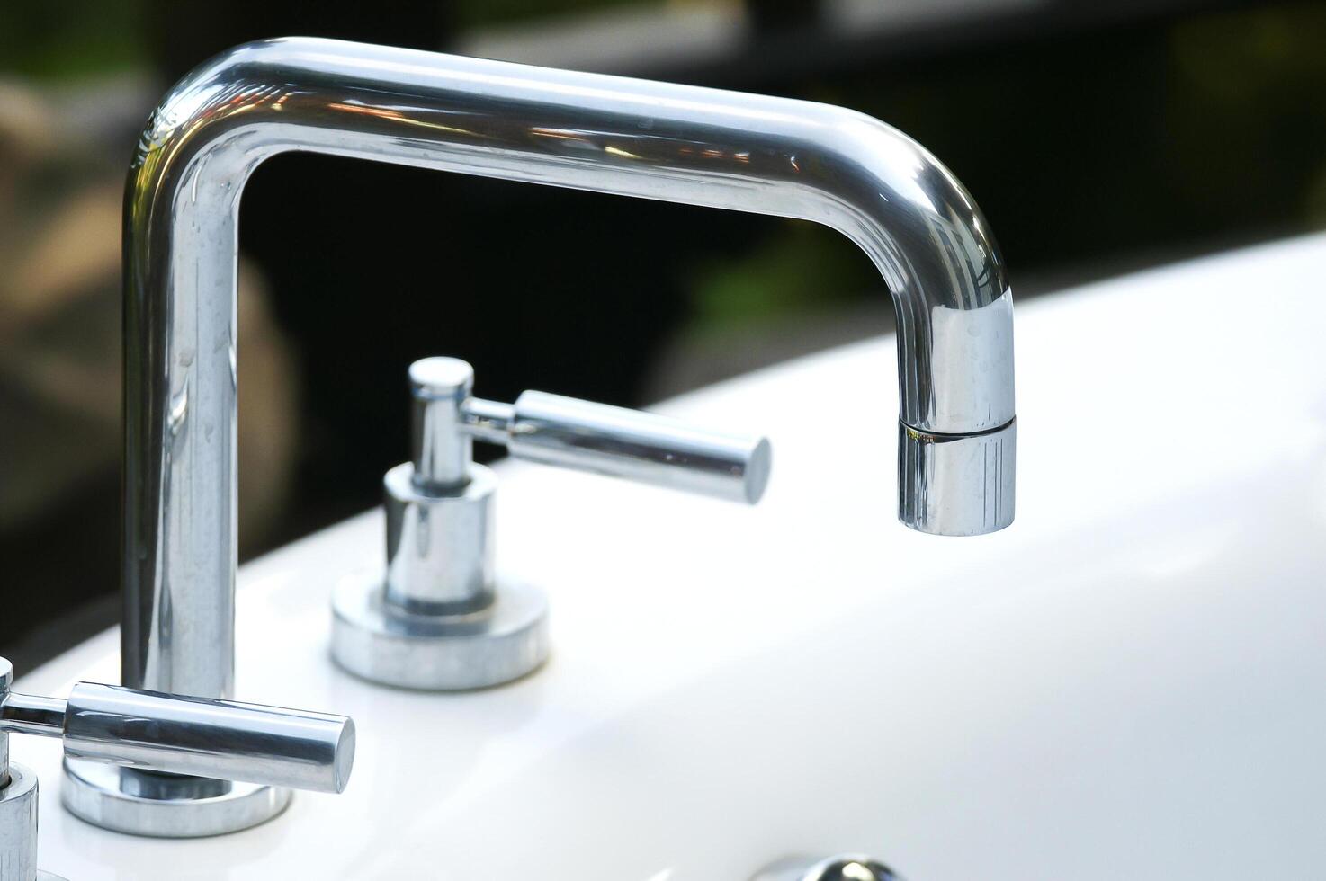 A close up of two faucets on a white sink photo