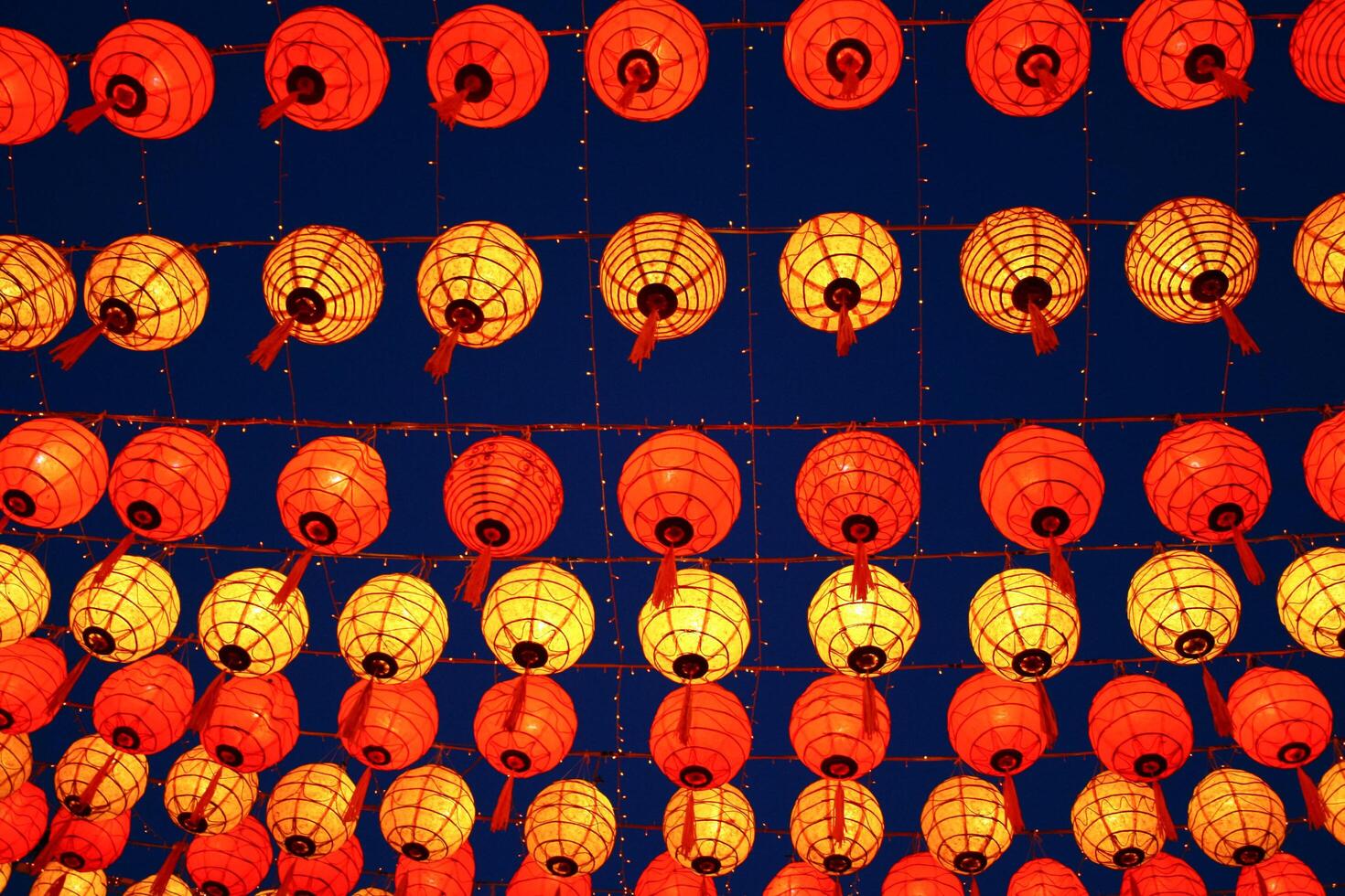 A bunch of orange and yellow lanterns hanging in the air photo