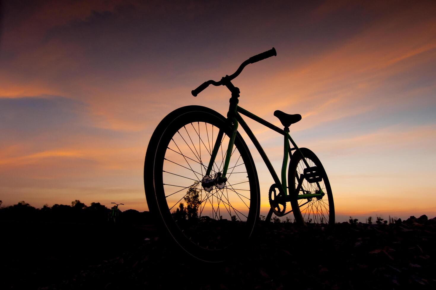 A bicycle is silhouetted against a sunset sky photo