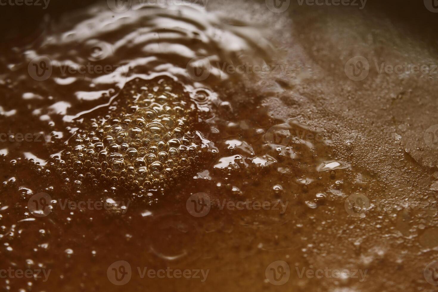 Boiling viscous liquid with orange color and bubbles photo