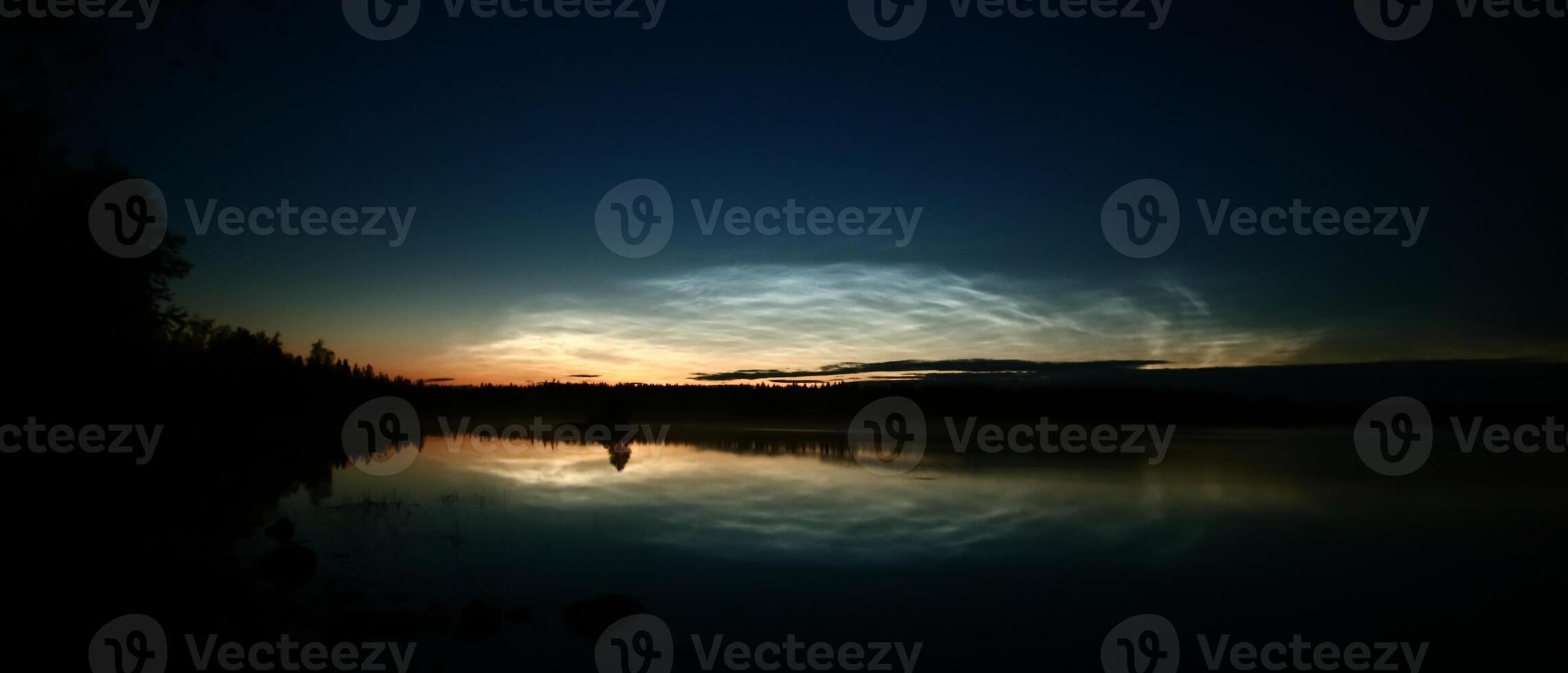 Illuminated cirrus clouds at dusk over lake Malgomaj in Vasterbotten, Sweden photo