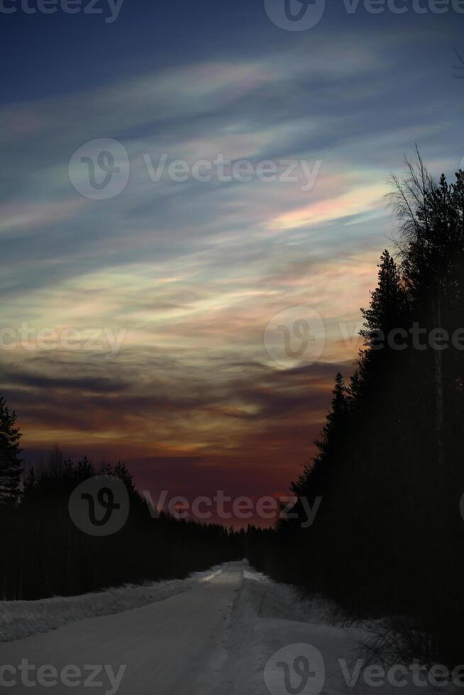 Nacreous clouds in the morning over winter road photo