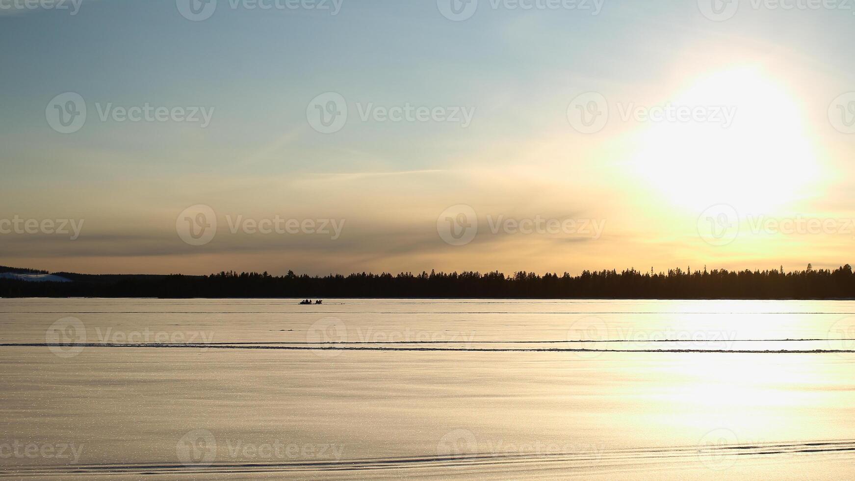 Silhouettes of group of people with snowscooter on frozen solid lake Norsjon in Vasterbotten, Sweden photo
