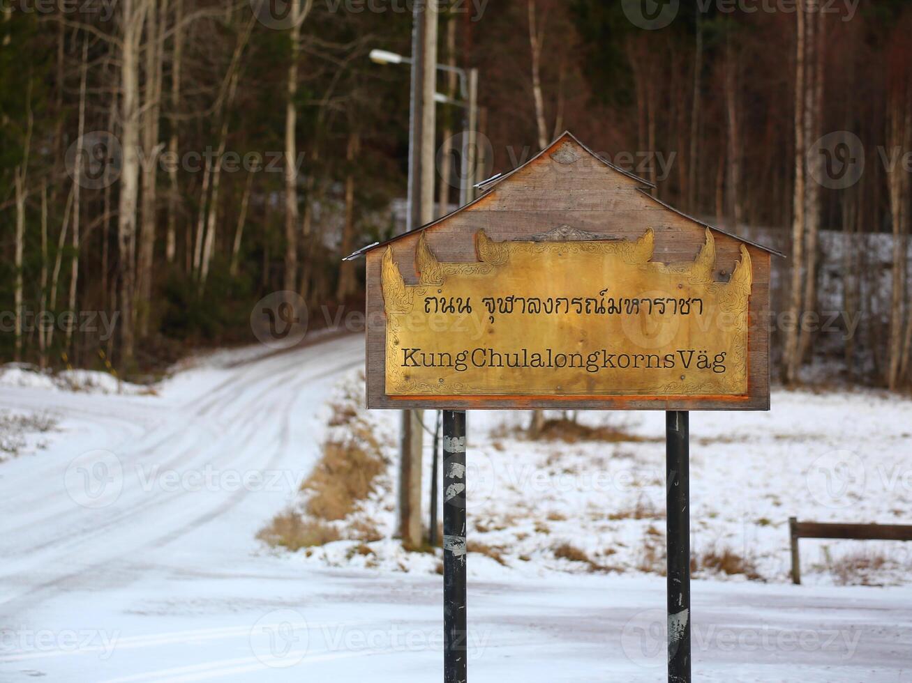 Gold plated street sign with the name of the road Kung Chulalongkorns Vag in Thai and Swedish photo