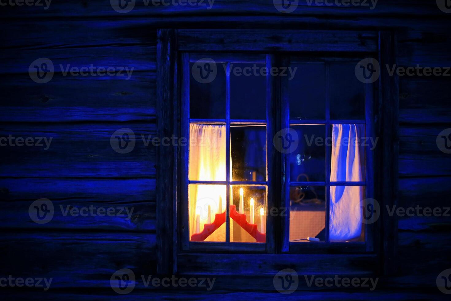 Window of log hut with christmas decoration in blue evening light photo