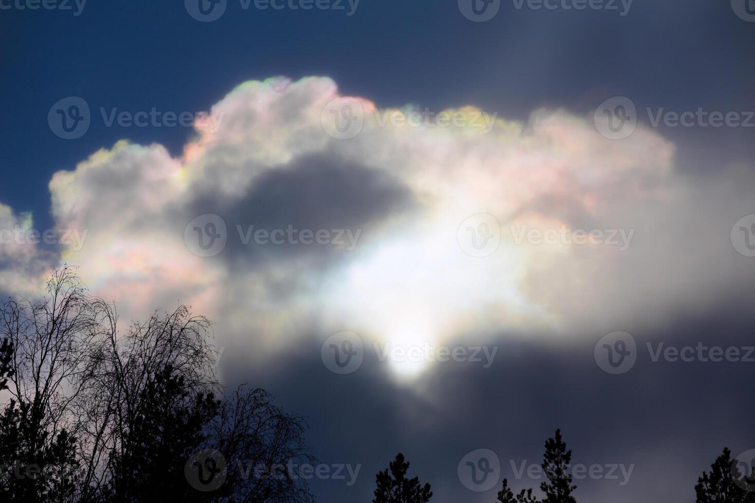 Sun behind rainbow colored clouds in April photo