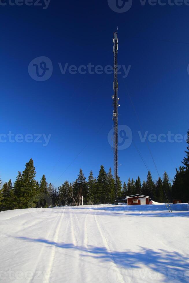 Telecommunications tower at the snowy peak of Amliden in Sweden photo