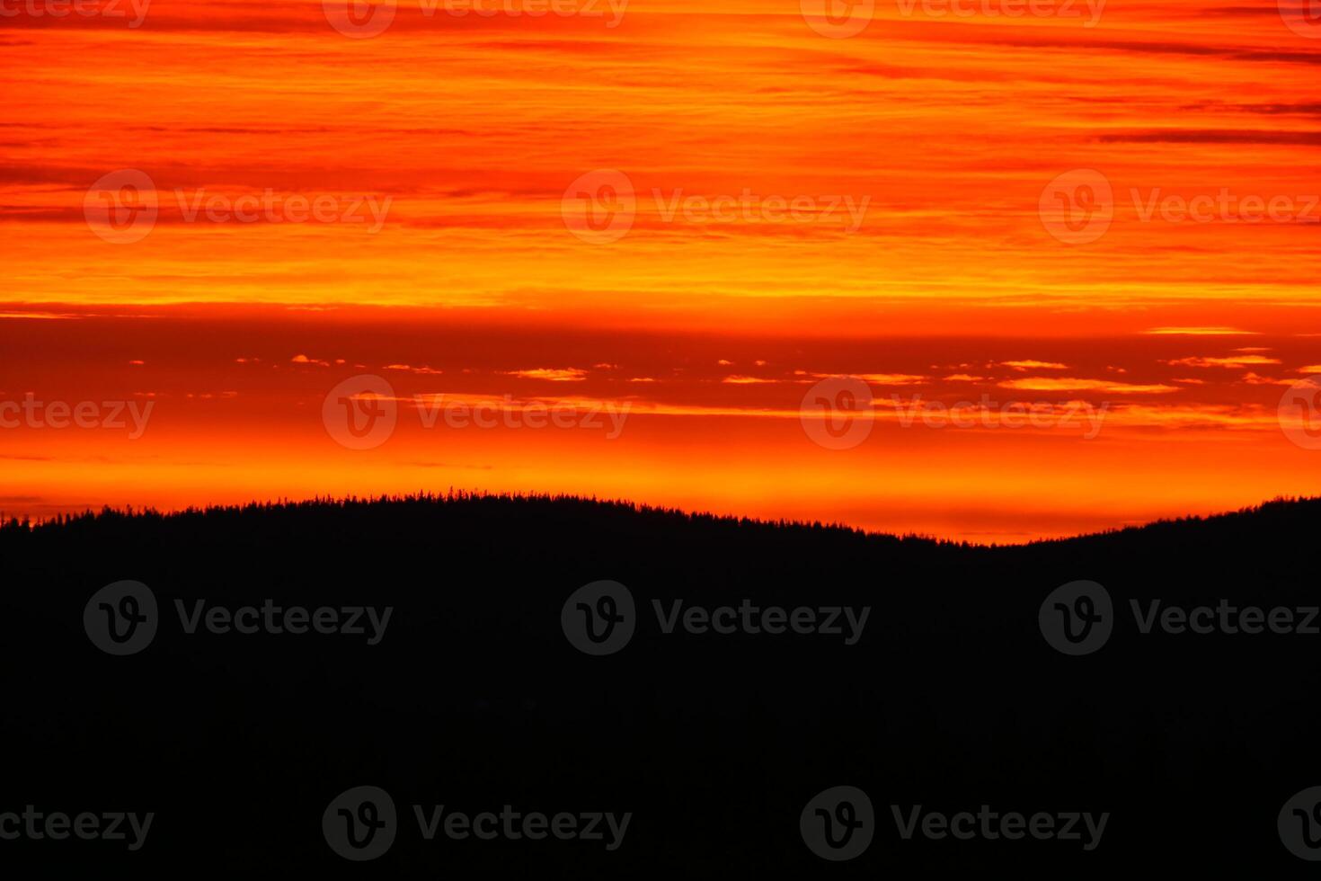 Layered cloudscape and dusk over mountain forest silhouette photo