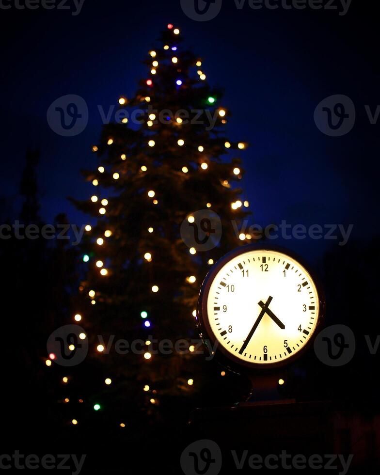 Clock and christmas tree in the night symbolizing christmas time photo