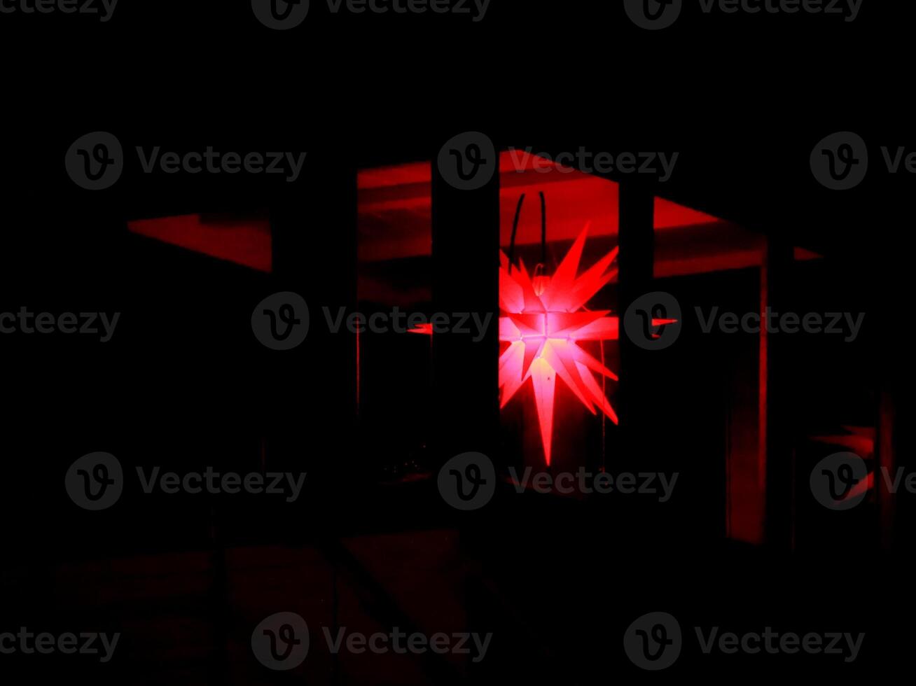 Red Moravian star hanging in a dark patio photo
