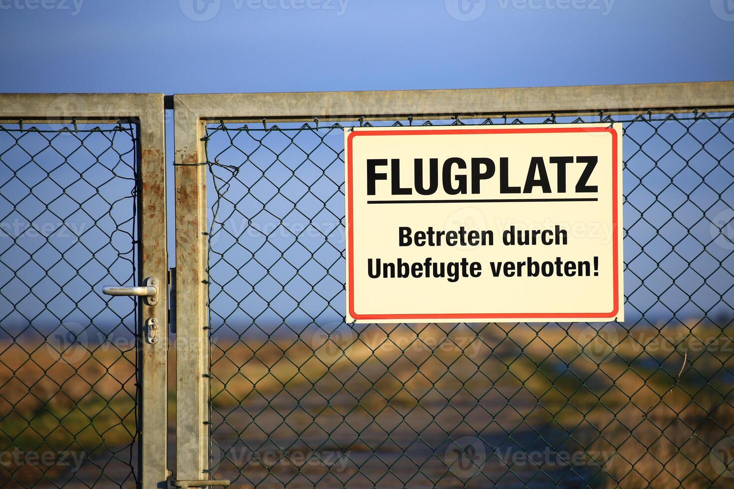 Sign at a a gate saying Flugplatz - Betreten durch Unbefugte verboten Airport - No trespassing by unauthorized personnel photo