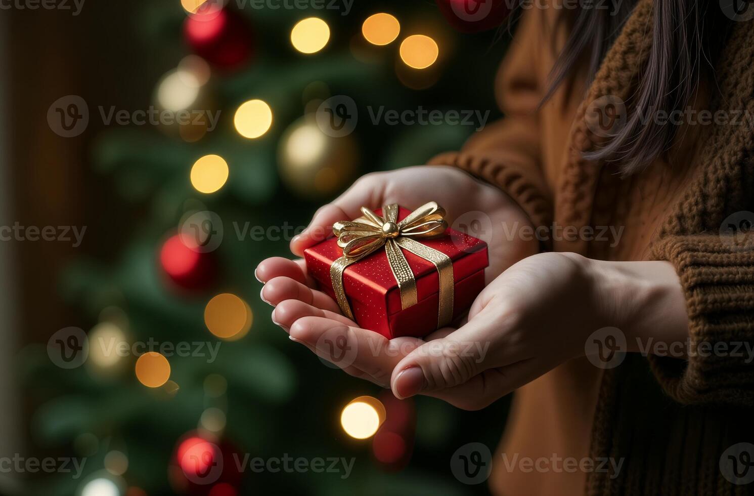Hands holding beautiful present, decorated Christmas tree in the background, close-up photo