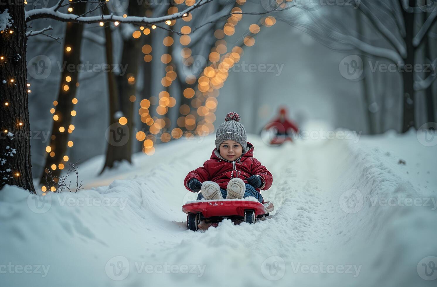 Kid is amusing sledding down snow hill, child is having fun during New Year holidays, Christmas tree background photo