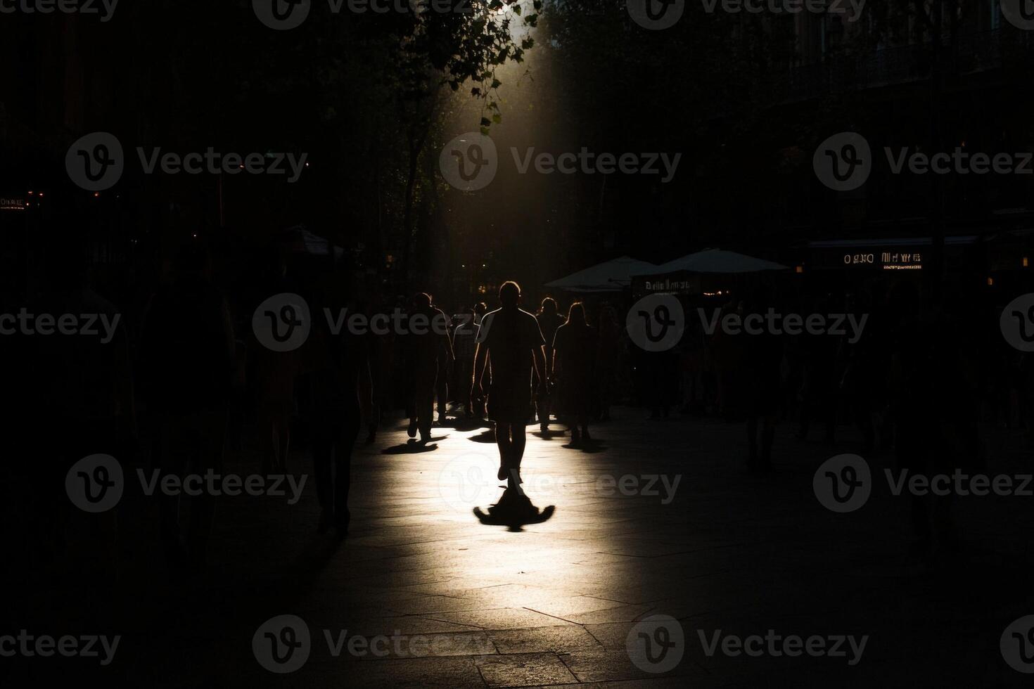 A person walking in the street with the sun shining through the trees photo