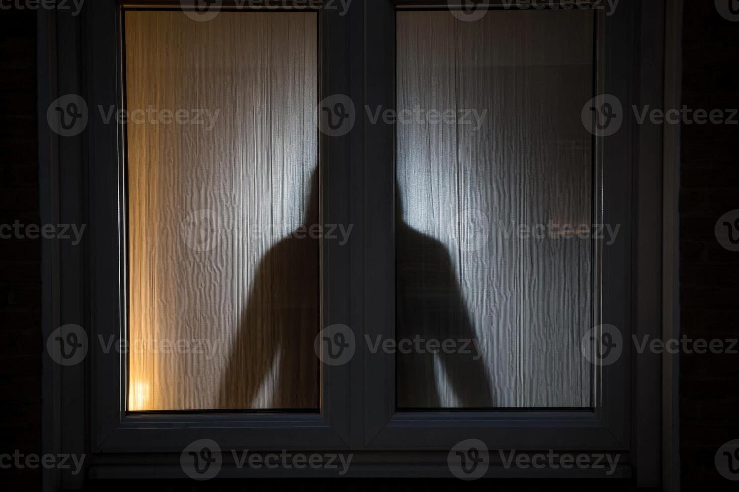 A person is standing in front of a window at night photo