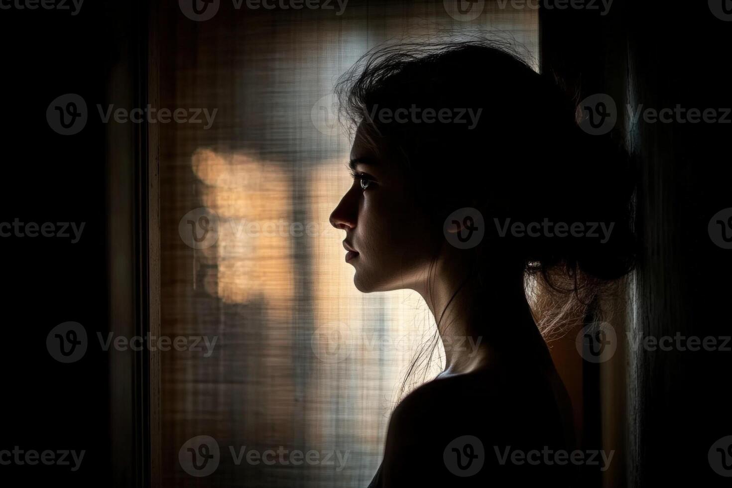 A woman is looking out the window in the dark photo