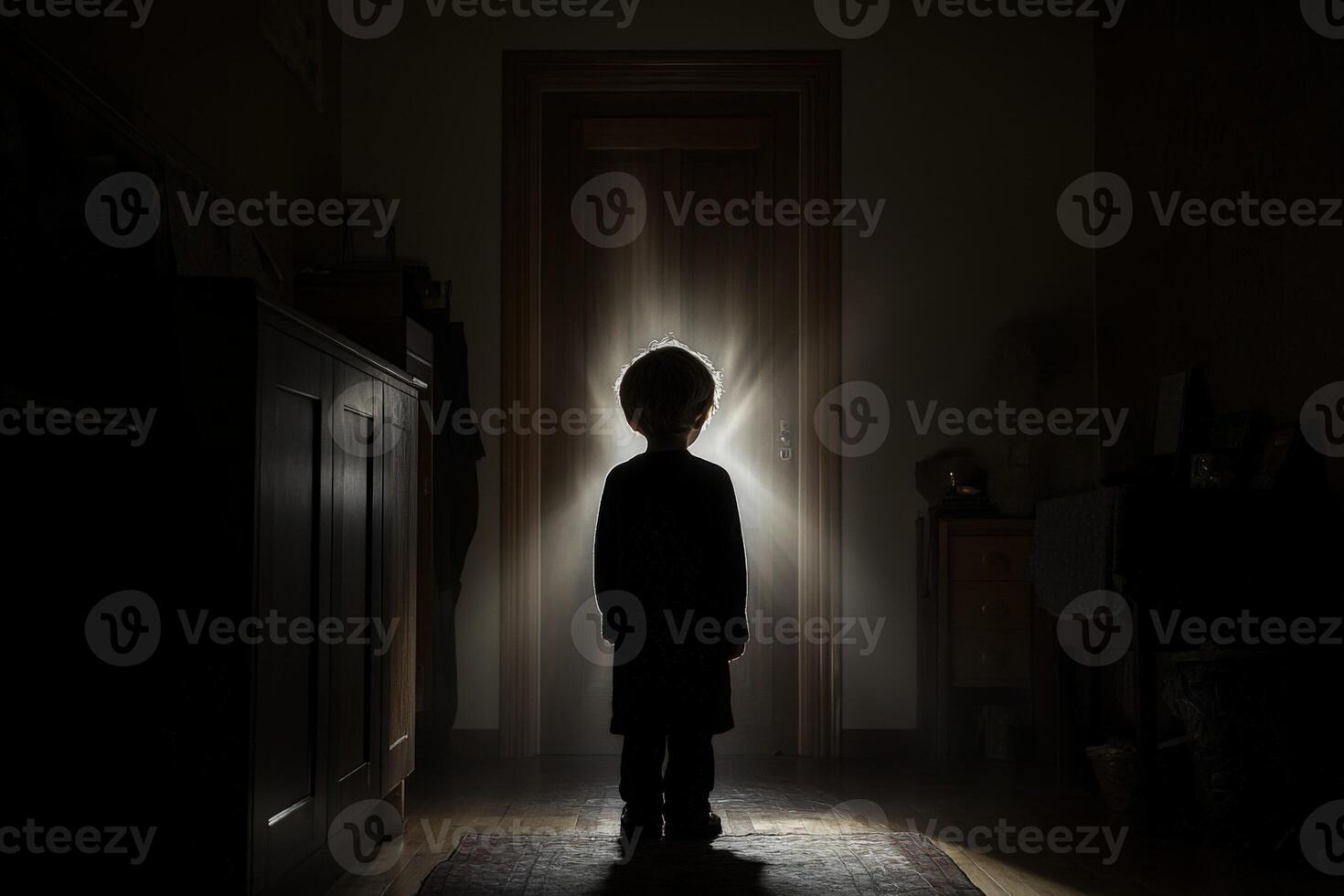 A child standing in the dark in front of a door photo