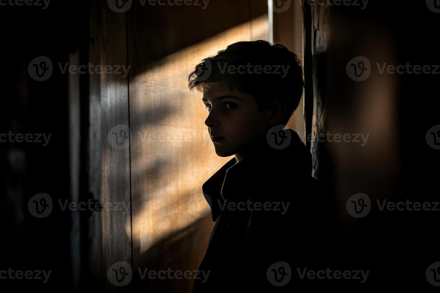 A boy stands in the shadows of a doorway photo