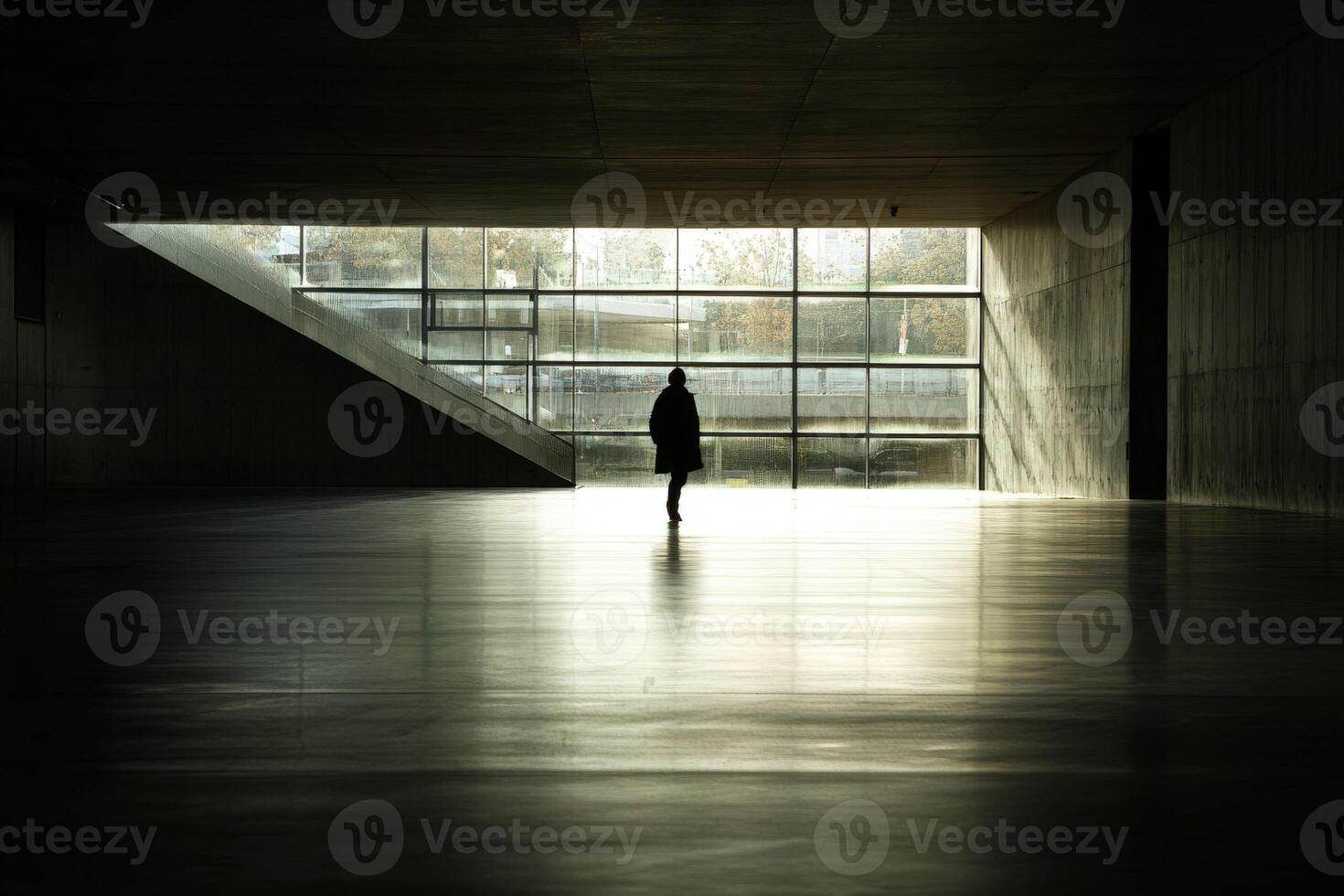 A person walking in an empty room with a large window photo