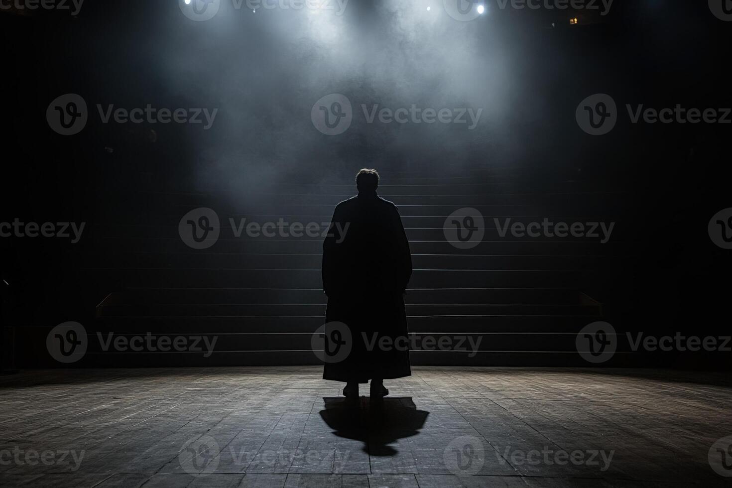 A man in a black cloak stands in front of a stage photo