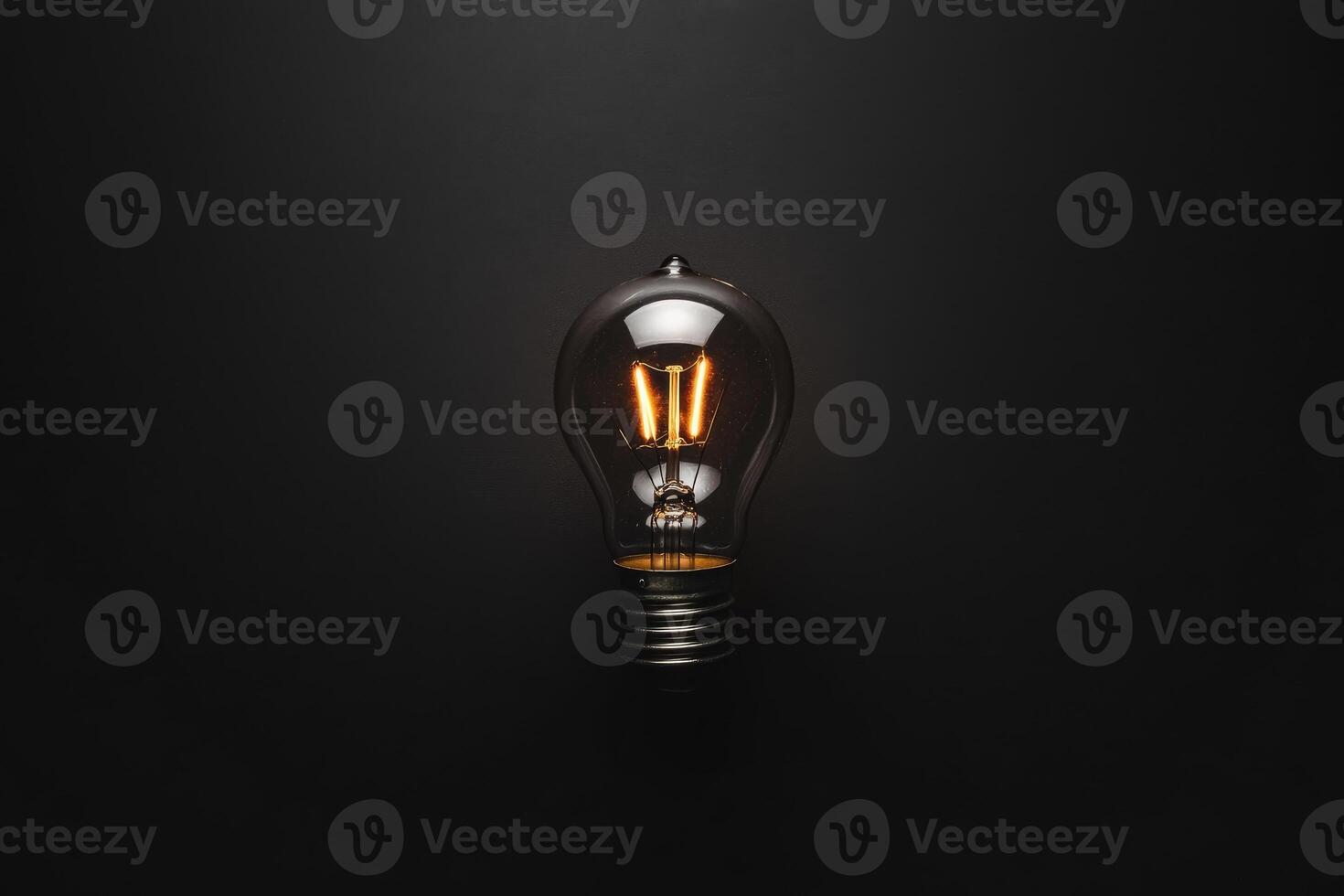 A Single Illuminated Light Bulb Against a Dark Background photo