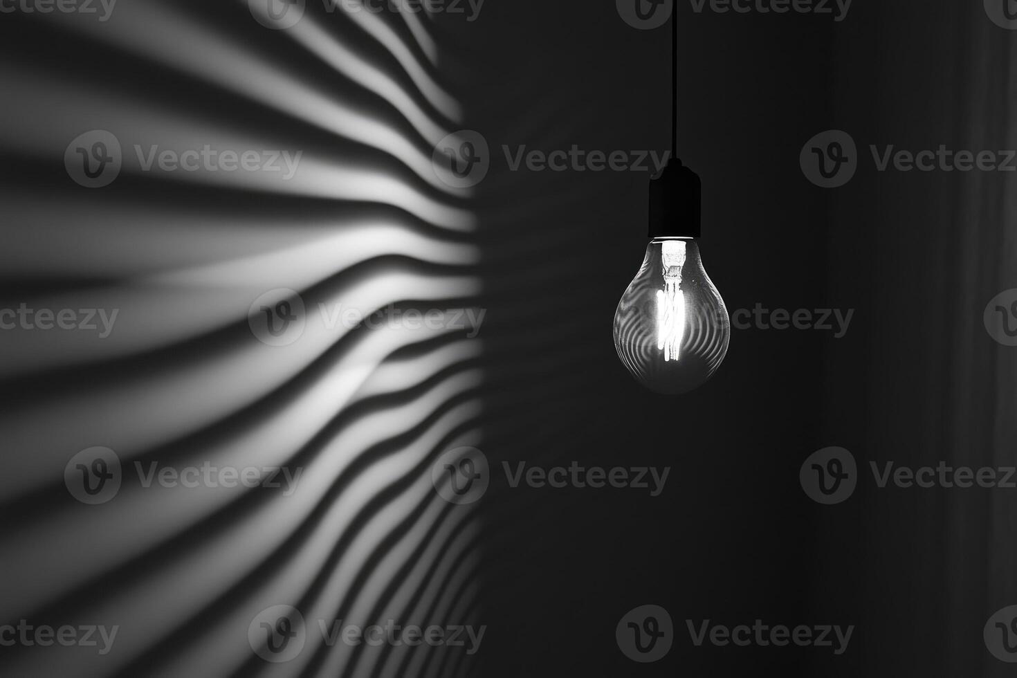 A Single Light Bulb Hanging Against a Wall with Curved Shadows photo