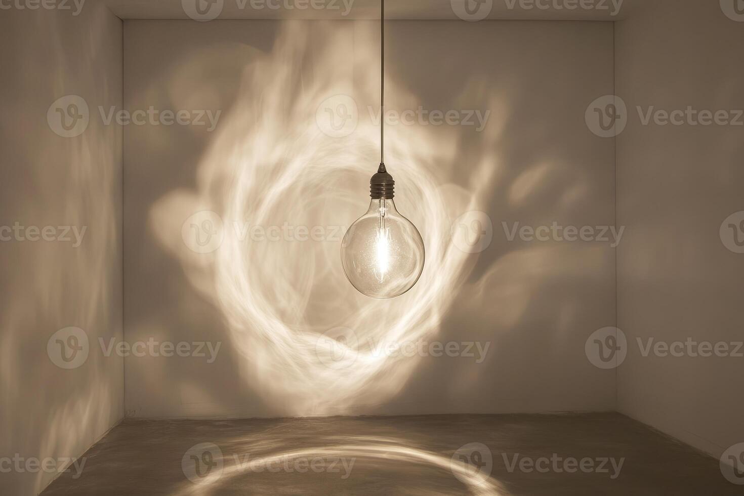 A single light bulb hangs from the ceiling in a white room, casting a swirling shadow on the wall. photo
