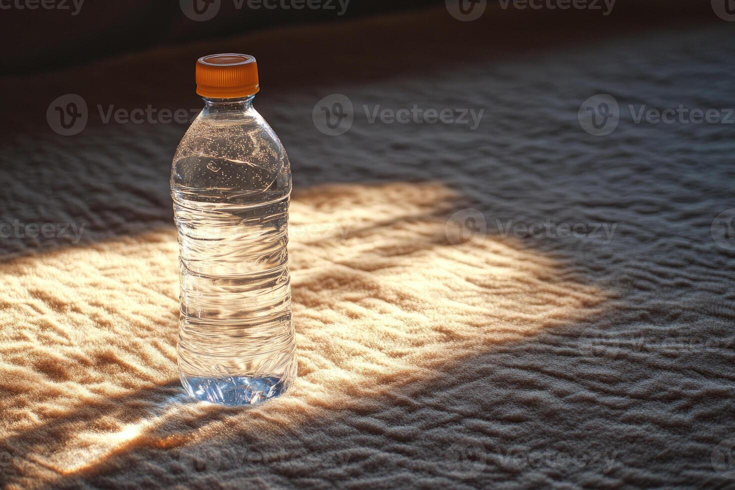 A Single Plastic Water Bottle with an Orange Lid on a Fabric Surface photo