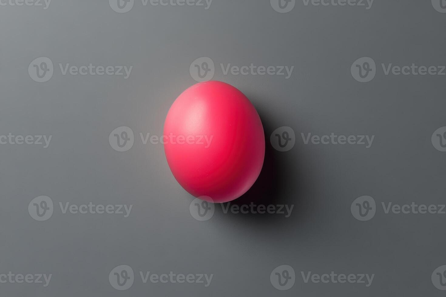 A single pink sphere rests on a grey surface photo