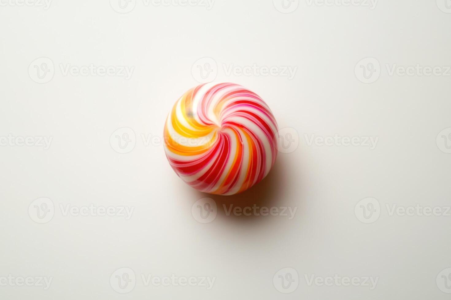 Swirled hard candy rests on white background photo