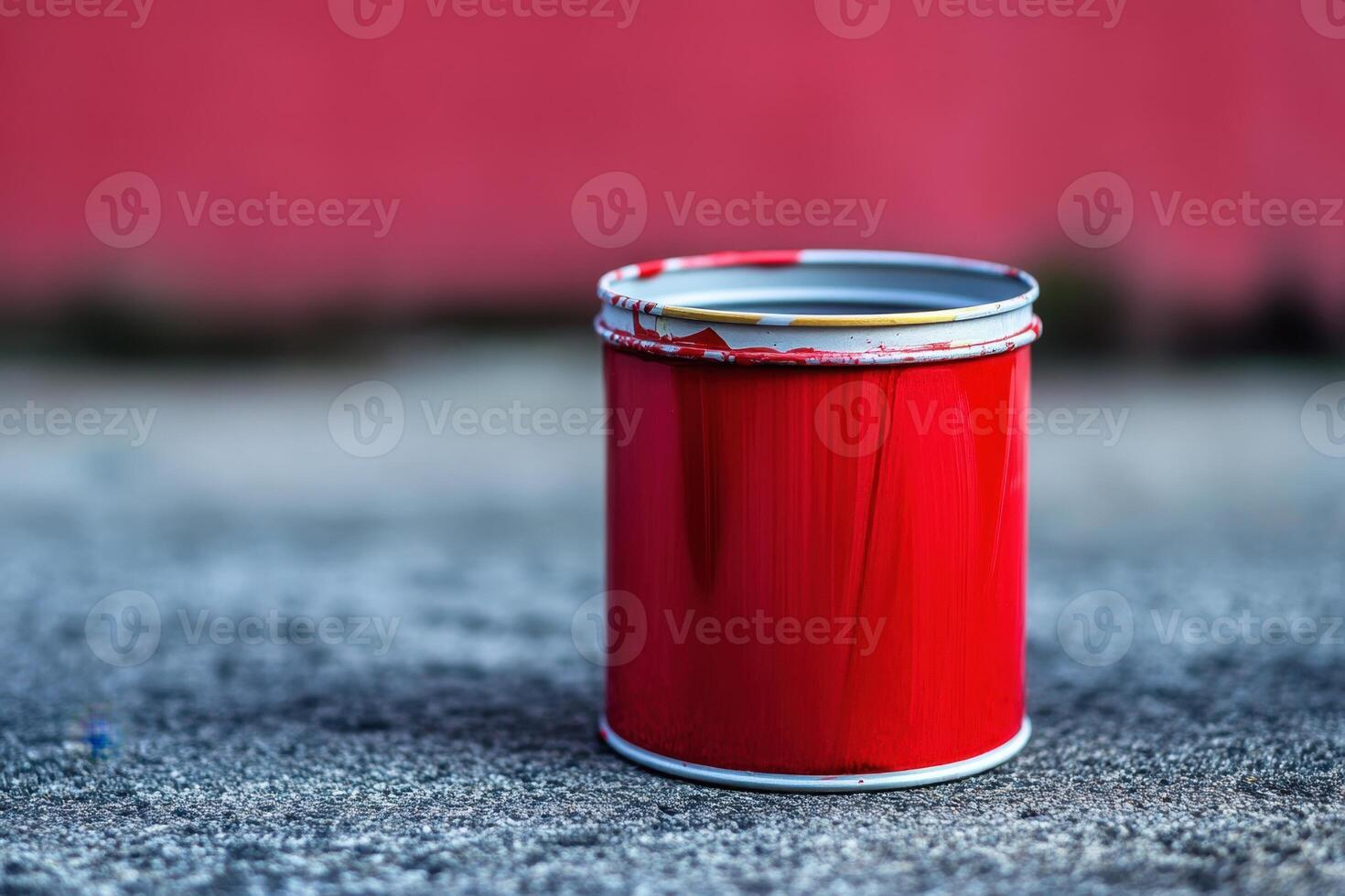 Red paint can sits on grey ground against red background photo
