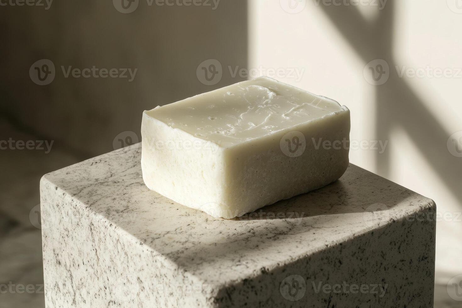 A single bar of off white soap rests on a stone pedestal photo
