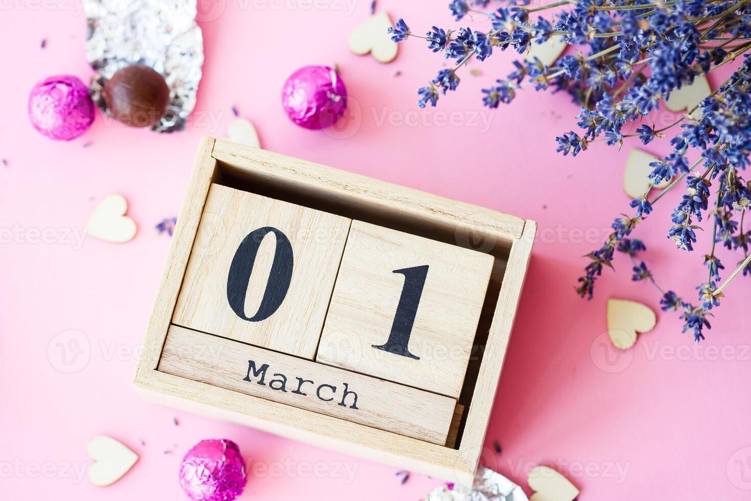 Wooden calendar with the date of March 1 on a pink background, a place for an inscription, The first day of spring, a dry branch of lavender photo