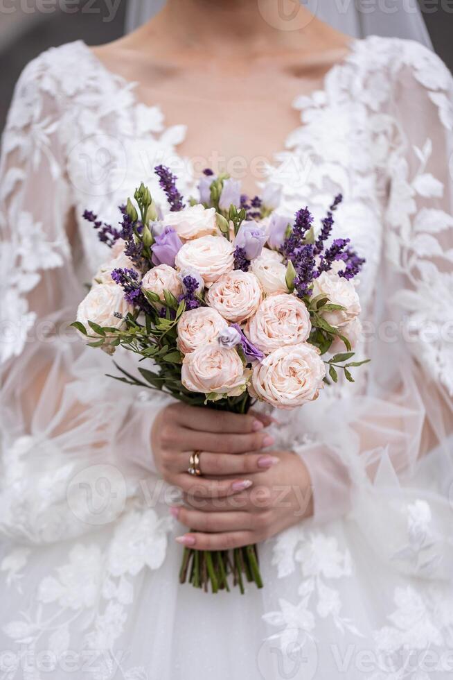 Hands of the bride close-up with a bouquet of fresh beautiful flowers. Attribute of the bride photo