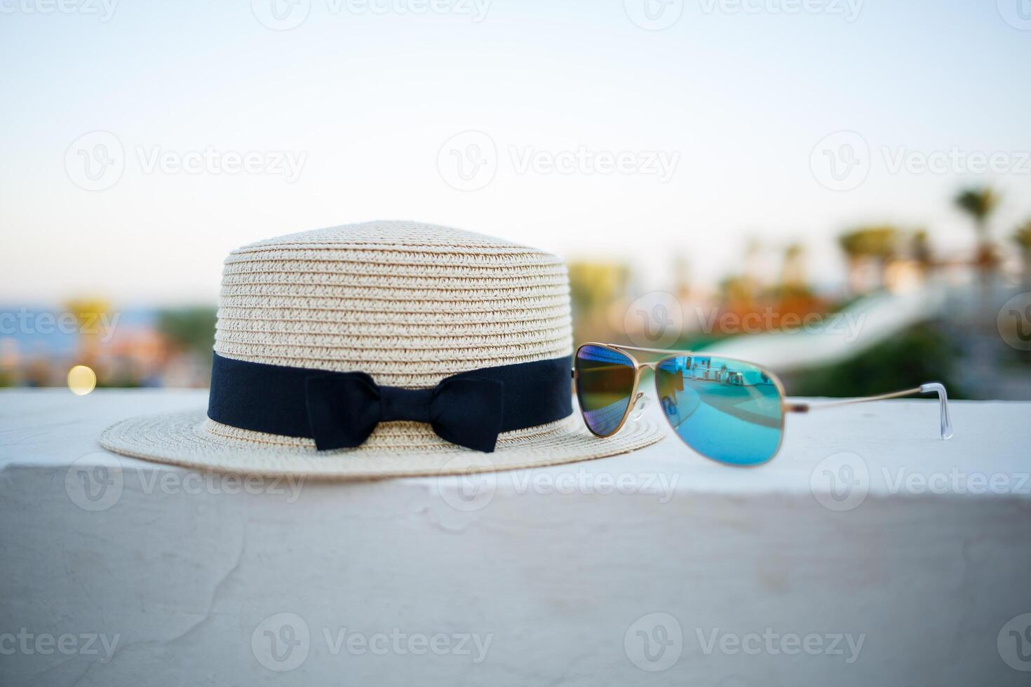 Women's summer hat and glasses lie on the terrace overlooking the sea photo