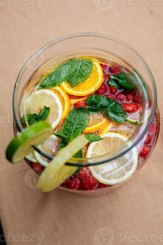 Refreshing lemonade with fresh fruit orange lemon cherry and mint leaves. Delicious non-alcoholic fruit cocktail in a jug photo