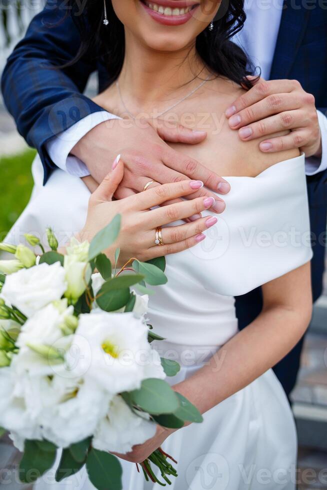 Hands of the bride close-up with a bouquet of fresh beautiful flowers. Attribute of the bride photo