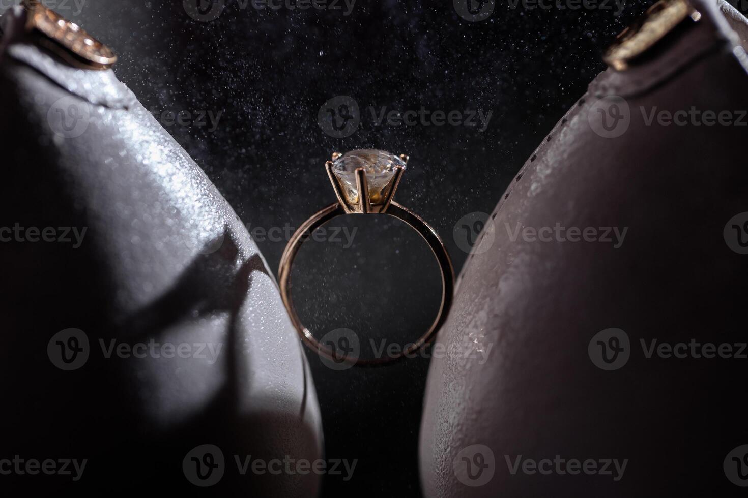 Gold ring of the bride with a pebble between white shoes with heels. Bride's precious ring photo
