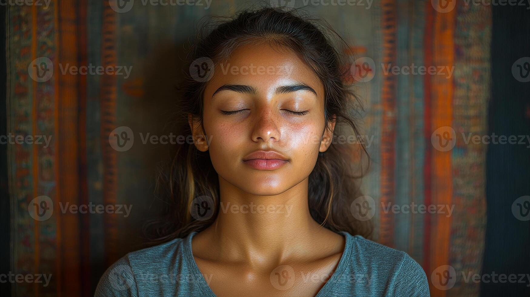 A woman is sitting with her eyes closed and her head tilted to the side. She has a slight smile on her face photo