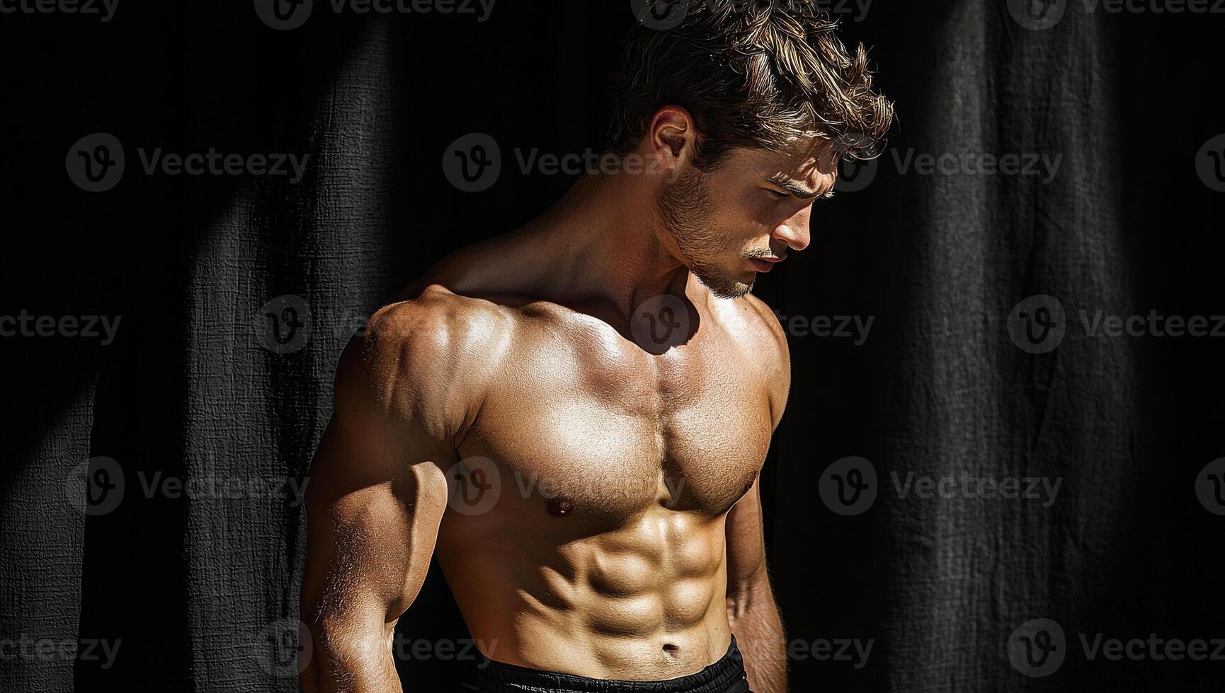 A man with a muscular chest and arms stands in front of a black curtain. Concept of strength and confidence, as the man's physique is prominently displayed photo