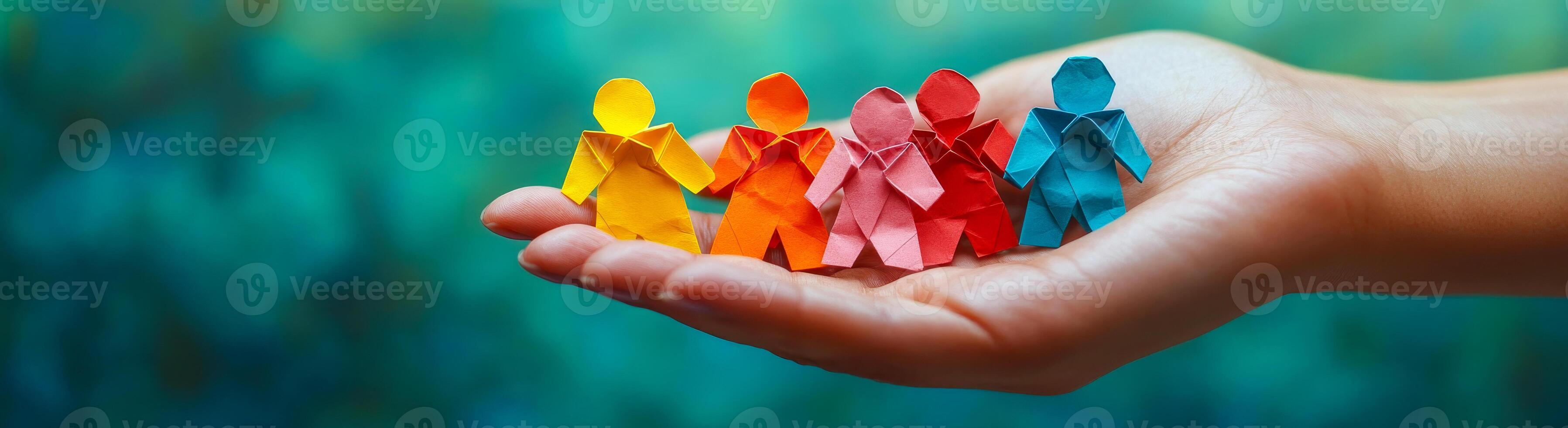 A hand holding a stack of colorful paper cutouts of people. The people are of different colors and sizes, and they are arranged in a row. Concept of unity and togetherness photo