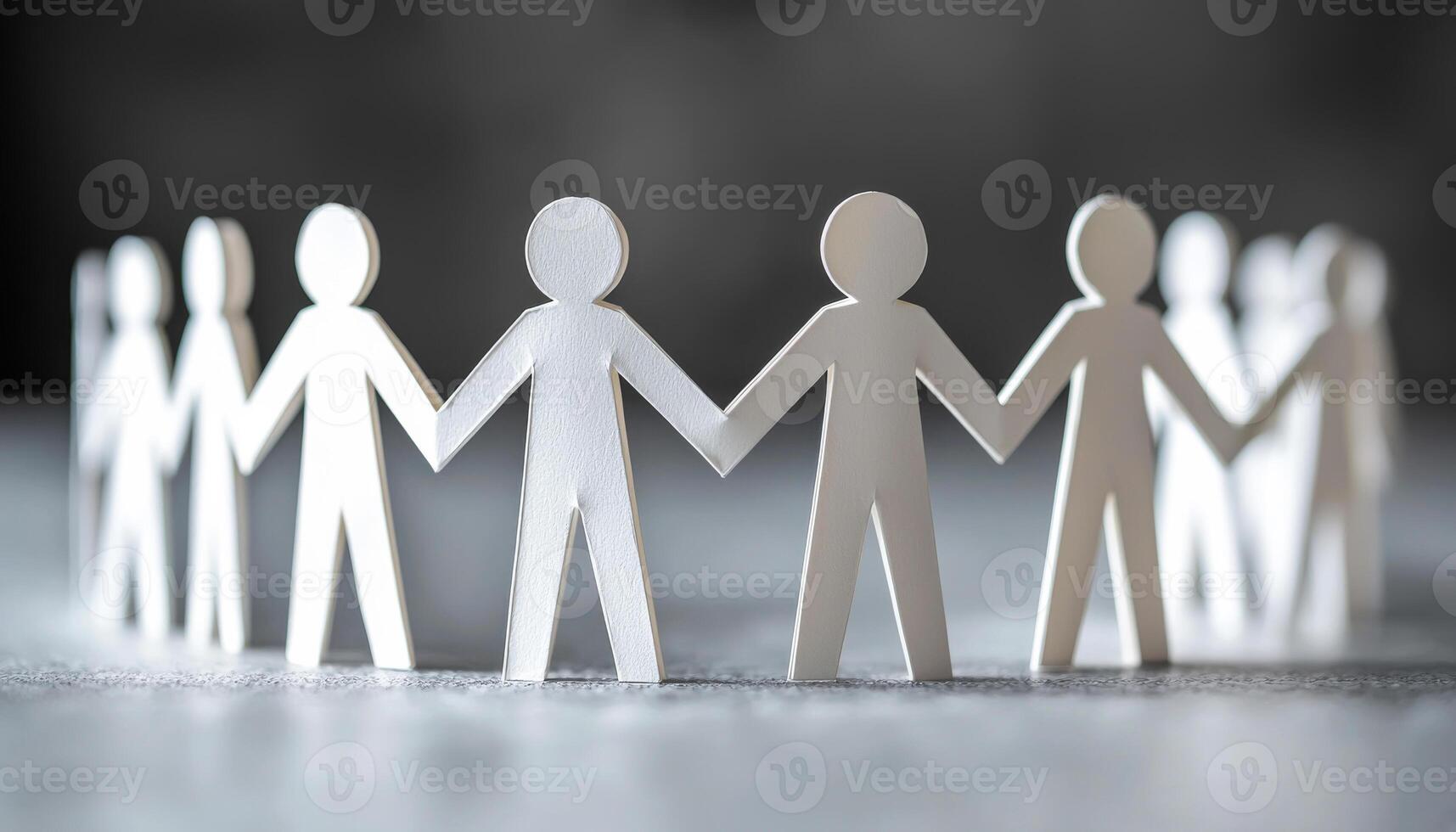 People holding hands in unity with paper cutouts. Paper cutouts of people holding hands arranged in a circle symbolize unity and togetherness. photo