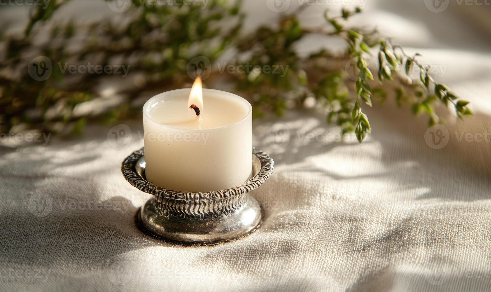 A candle is lit on a silver holder photo