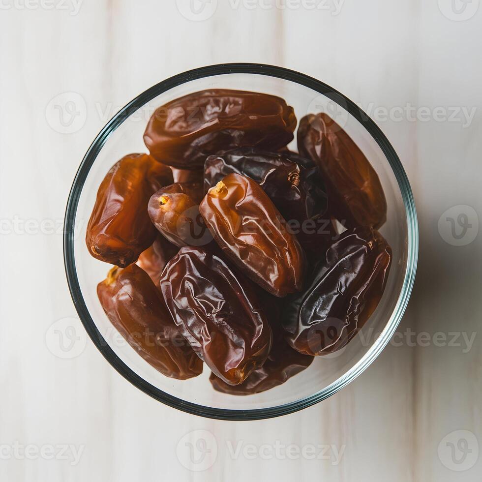 Glass bowl of dried dates, rich textures against white background For Social Media Post Size photo