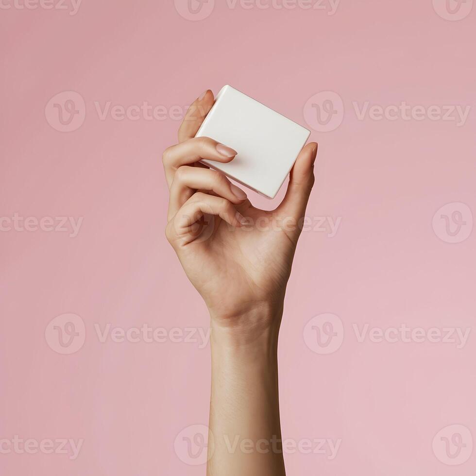 Female hand holds rectangular white object, soft pink background, minimalist elegance. For Social Media Post Size photo